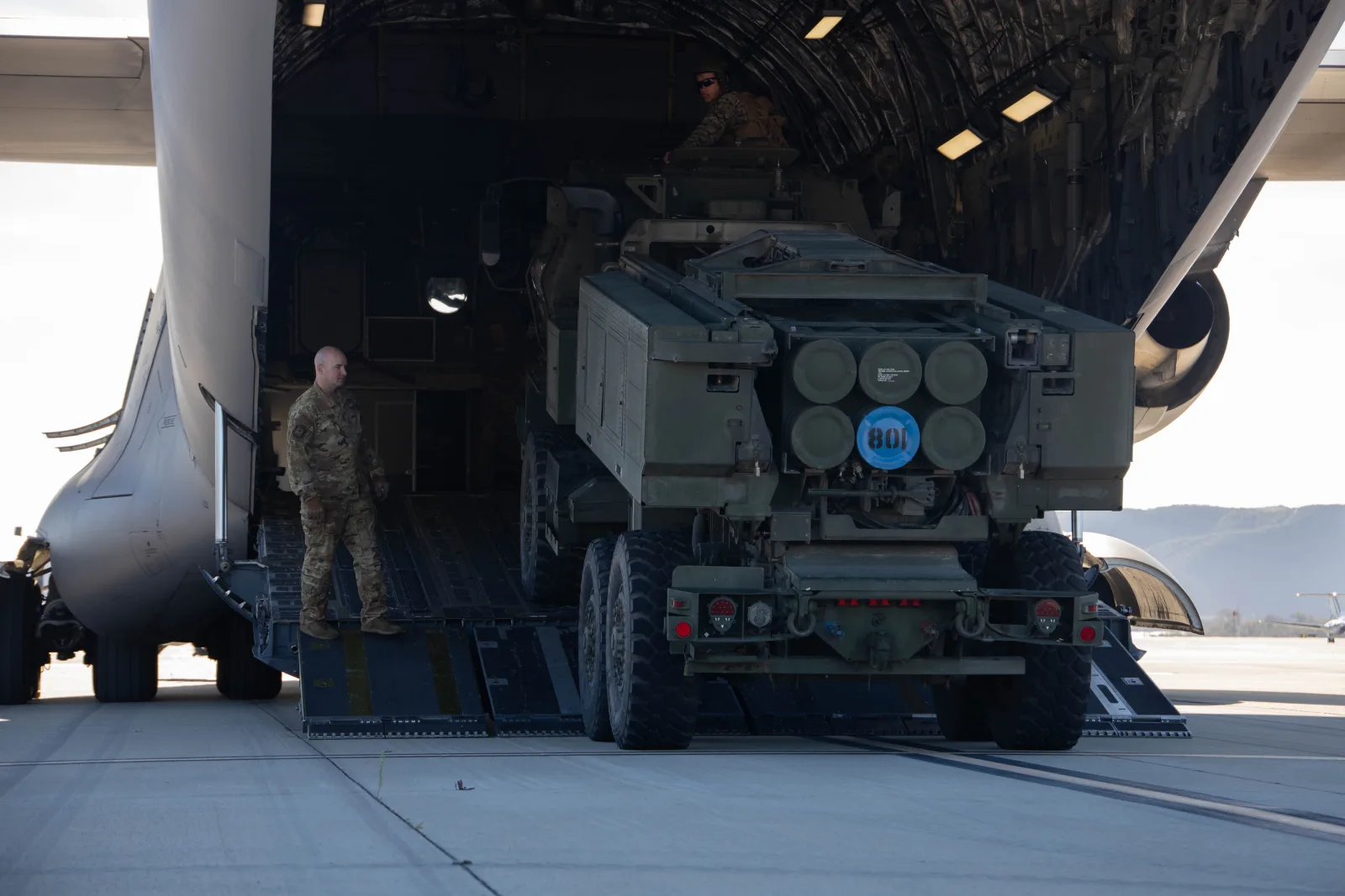 جندي أمريكي يوجّه عناصر من الفوج الخامس للمدفعية البحرية بجانب شاحنة نقل قرب منصة HIMARS ضمن دعم أوكرانيا