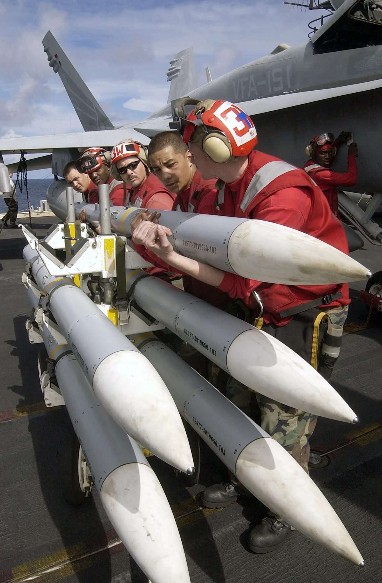أفراد بحرية أمريكيون يجهزون صاروخ AIM-120 AMRAAM من إنتاج RTX (رايثيون) لتحميله على مقاتلة