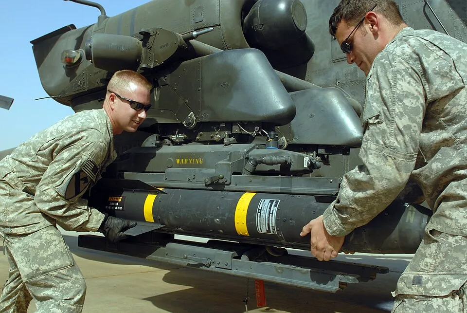جنود من الجيش الأمريكي يحمّلون صاروخ Hellfire على حاملة الصواريخ في مروحية أباتشي AH-64D بقاعدة كامب الطاجي في العراق