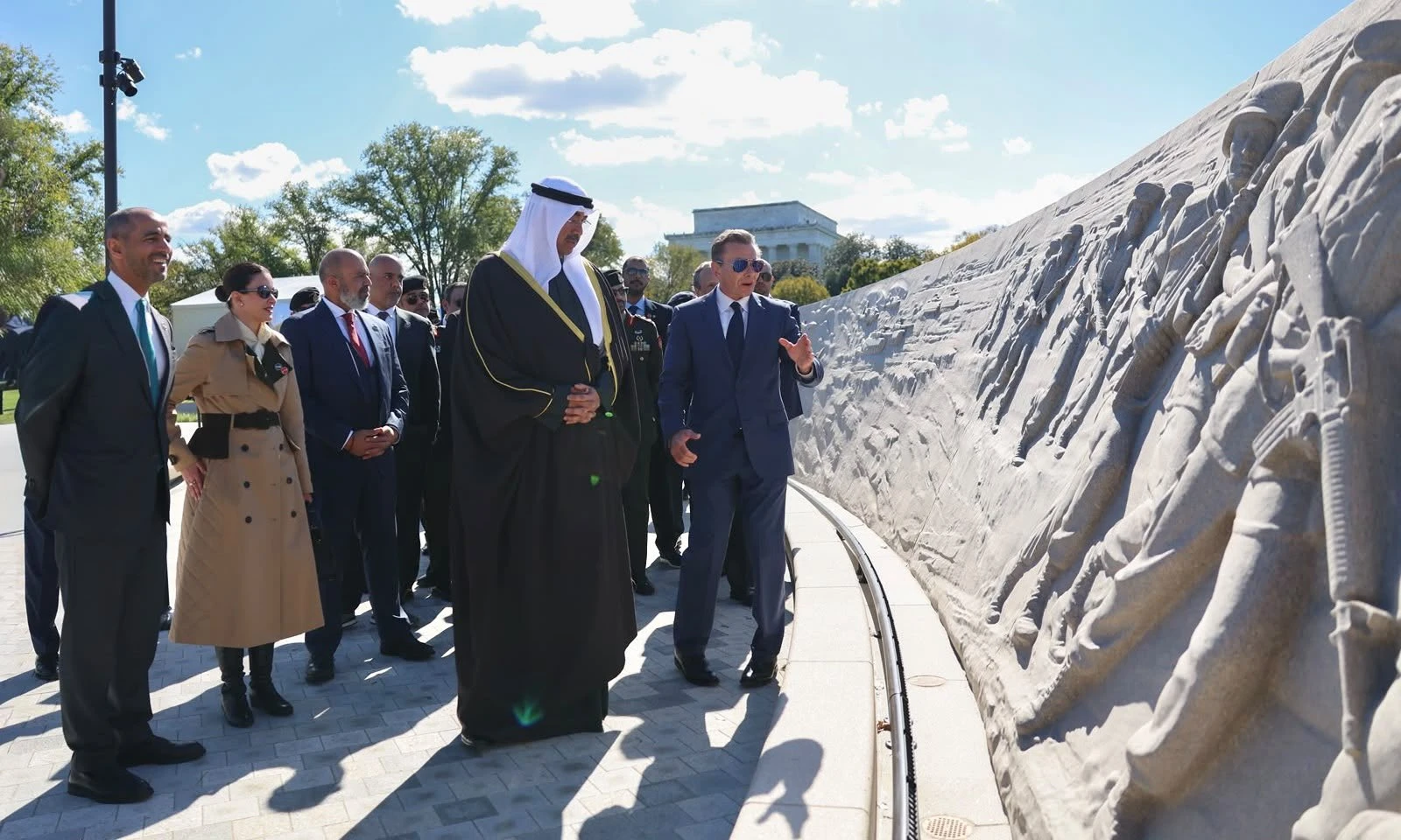 وزير الدفاع الكويتي يتجول أمام الجدار المنحوت الذي يروي تحرير الكويت في نصب درع الصحراء وعاصفة الصحراء