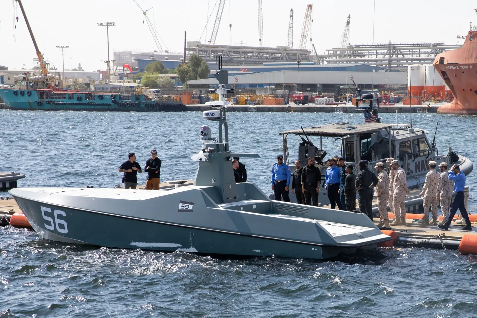 ضابط من البحرية الإماراتية إلى جانب بحارة أمريكيين ومركبة سطحية بحرية مسيّرة خلال تمرين Iron Defender في ميناء إماراتي